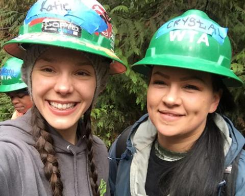 Two students wearing green hard hats