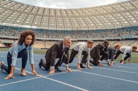 Business professionals in a sprinter’s stance on a stadium track capture the drive, competition, and urgency of today’s workplace.